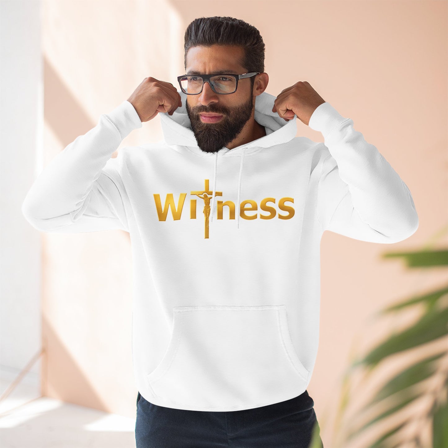 White pullover hoodie with gold “Witness” print and cross emblem, hood and front pocket.