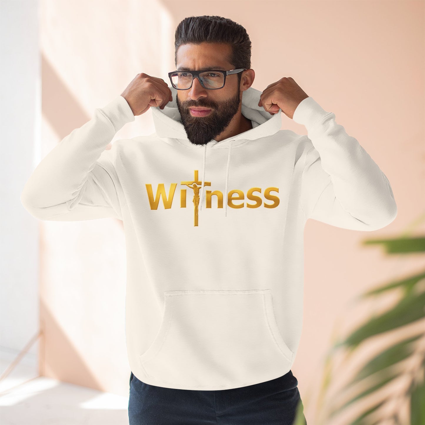 White pullover hoodie with gold “Witness” print and cross emblem, drawstring hood and pocket.
